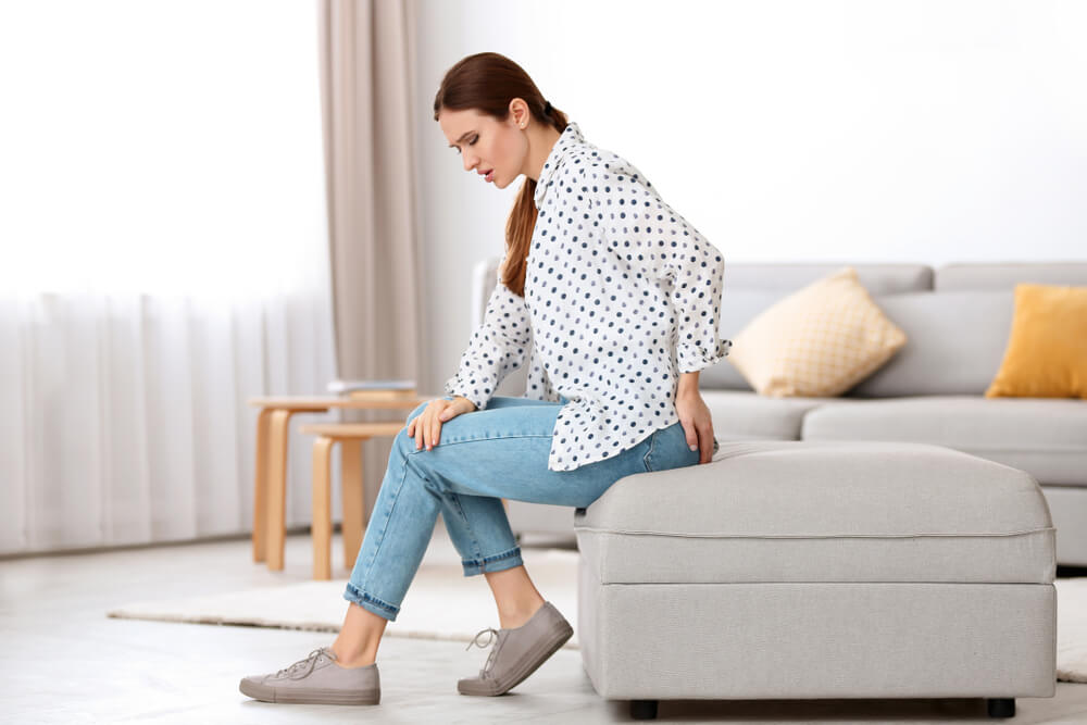 Young woman suffering from hemorrhoid at home