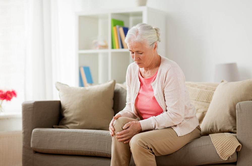 senior woman suffering from pain in leg at home