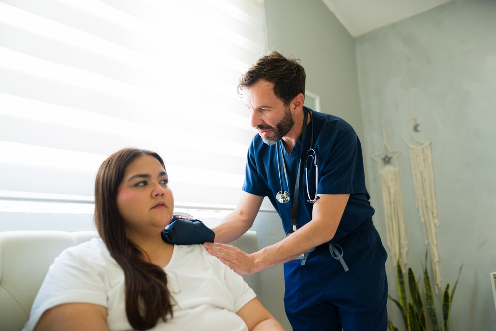 doctor visiting a recovering patient at her home, applying a warm compress to her shoulder after surgery