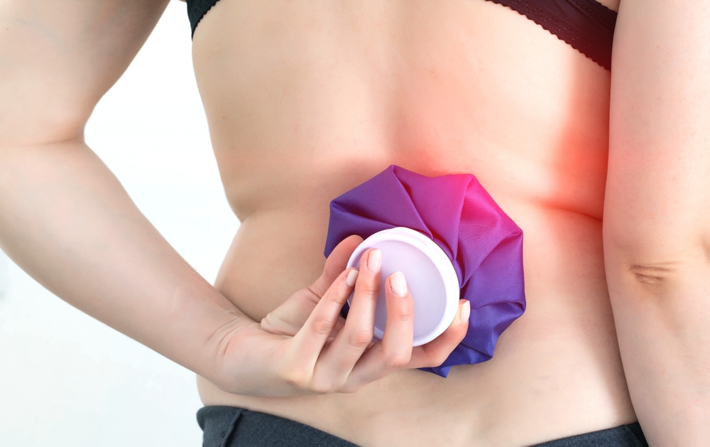 Girl holding a medical ice bag on the back of the spine