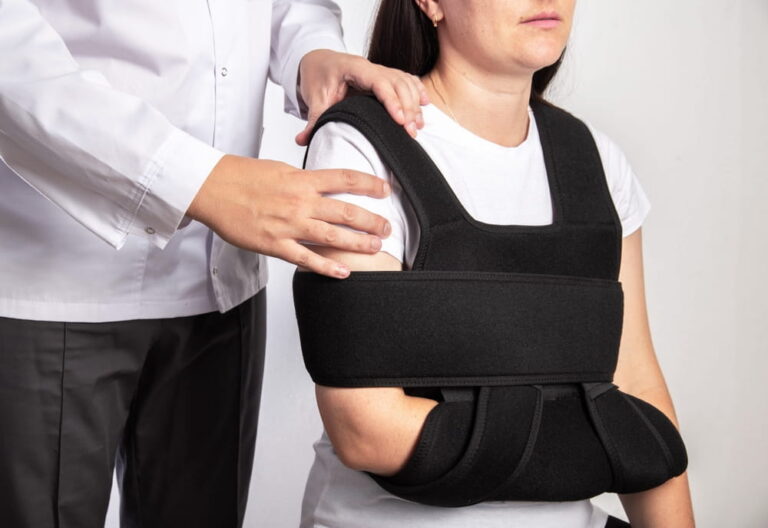 A doctor surgeon examines a girl's shoulder after surgery. Bandage on the shoulder joint during rehabilitation after surgery on the shoulder joint, tear of the shoulder cuff.